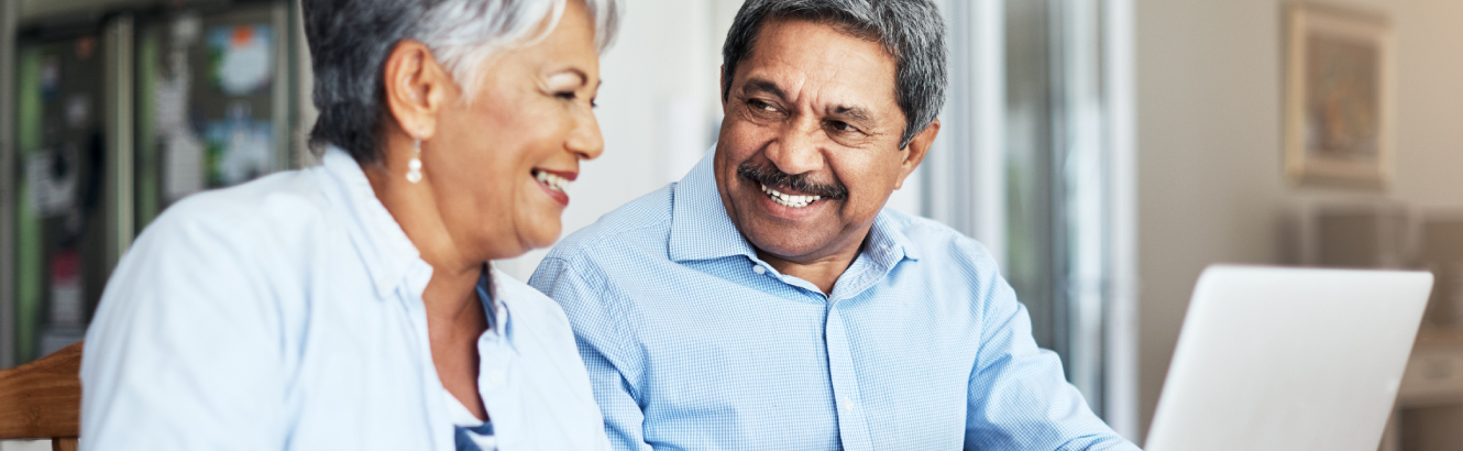 a mature couple smiling at computer